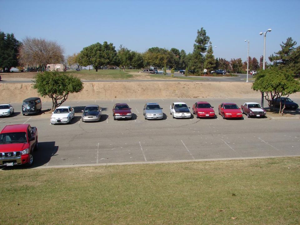Several cars parked in a lot, including a red pickup truck in the foreground