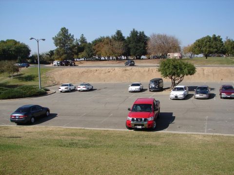 1992 Ford Taurus - A red pickup truck is parked in a lot with other vehicles under a clear sky.