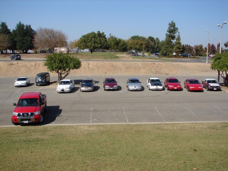 Parking lot with a red pickup truck and a line of sedans