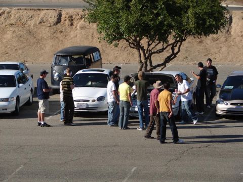 1992 Ford Taurus - A group of people gather around a white Ford Taurus, possibly at a car meet.