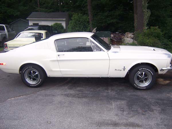 White 1968 Ford Mustang coupe, side view, chrome wheels, BFGoodrich tires, some bodywork visible