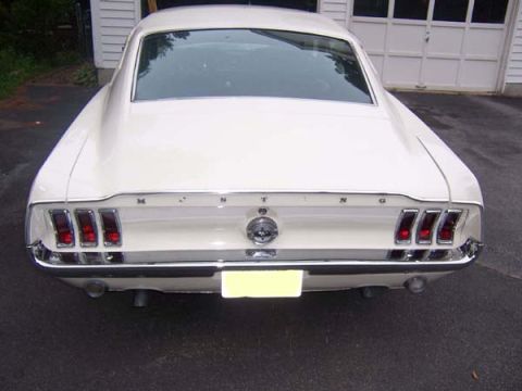 1968 Ford Mustang - Rear view of a white 1968 Ford Mustang, its iconic triple taillights and chrome bumper.