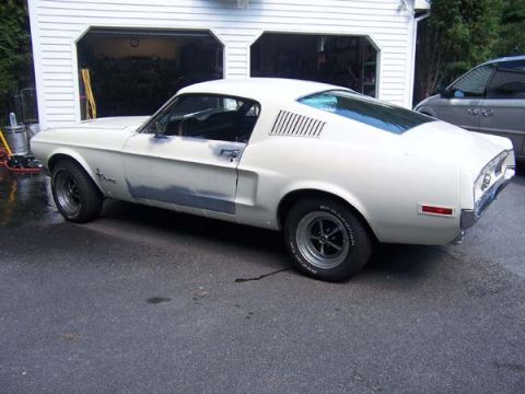 1968 Ford Mustang - This white coupe is in the process of being repaired and repainted, showing primer patches on its body panels.