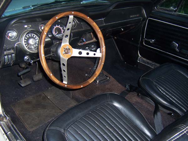 1968 Ford Mustang interior with wood-rimmed steering wheel and black vinyl seats