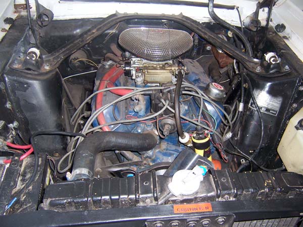 1968 Ford Mustang engine bay with blue engine block, carburetor, and red hoses