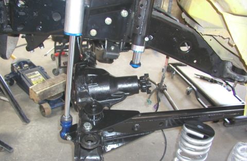 1984 Ford Bronco - Close-up view of front axle and suspension components, including shocks and a hydraulic jack.