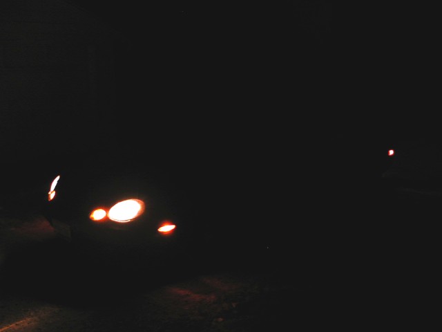 Very dark night photo with car headlights and parking lights glowing