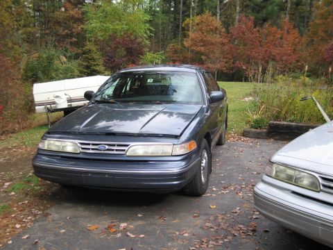 1991 Ford LTD Crown Victoria - A dark blue 1991 Ford Crown Victoria LTD sedan is parked in a driveway with its hood open, alongside another vehicle.