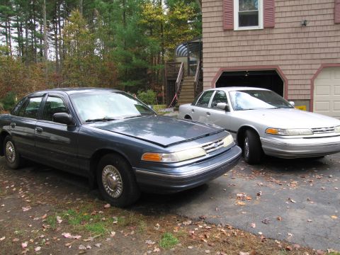 1991 Ford LTD Crown Victoria - Two Ford Crown Victoria sedans are parked outside a house with a garage.