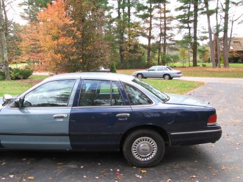 1991 Ford LTD Crown Victoria - A two-tone Ford Crown Victoria is parked in a driveway, with another sedan visible on the road behind it.