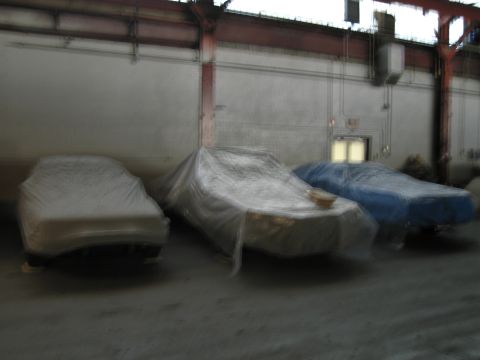 1991 Ford LTD Crown Victoria - Three vehicles are covered and parked inside a large industrial building.