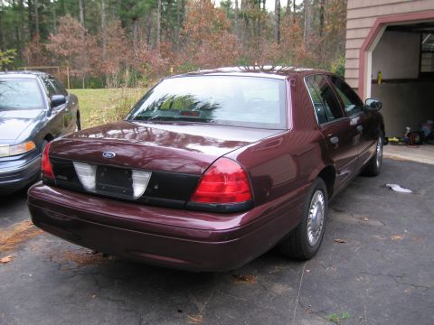 1991 Ford LTD Crown Victoria - A maroon Ford Crown Victoria is parked in a driveway next to another sedan, with a garage visible in the background.