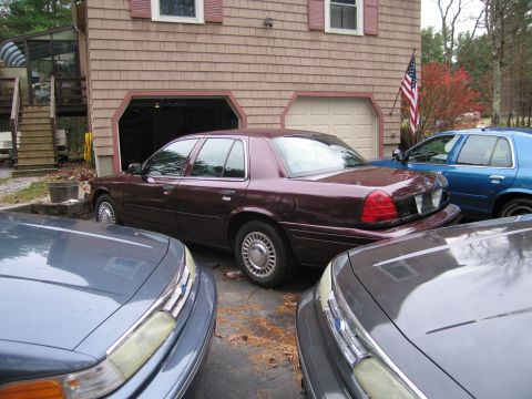 1991 Ford LTD Crown Victoria - A maroon Ford Crown Victoria is parked in a driveway with two other vehicles.
