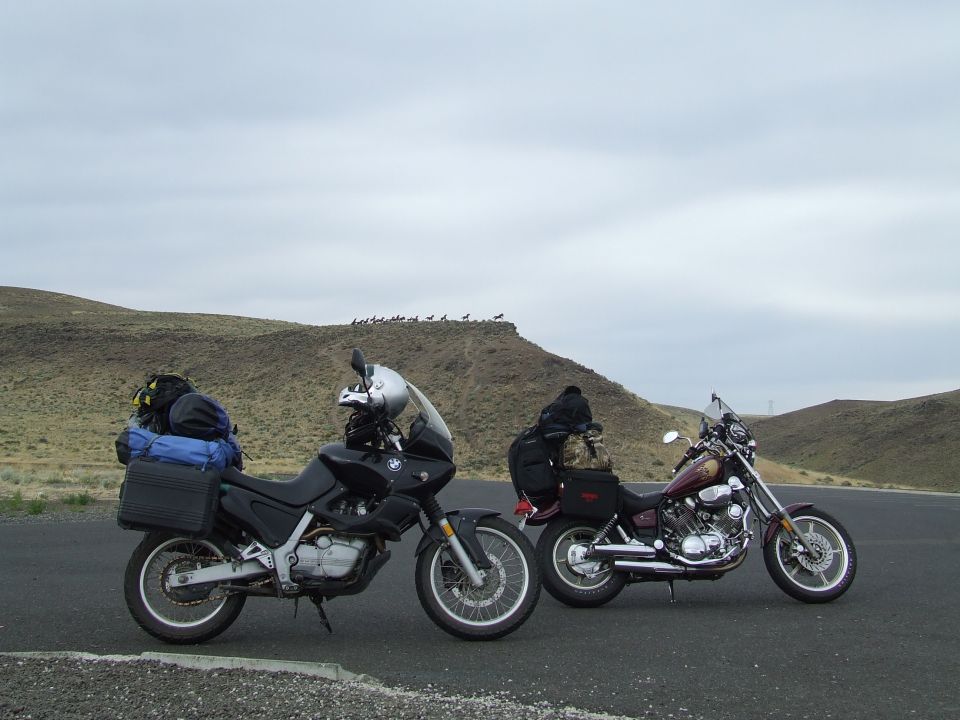 Black 1997 BMW F650 motorcycle with luggage, parked next to a maroon motorcycle on a paved road