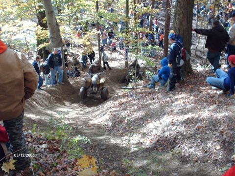1995 Ford Probe - An ATV is shown on a dirt track in a wooded area during an event with many onlookers.