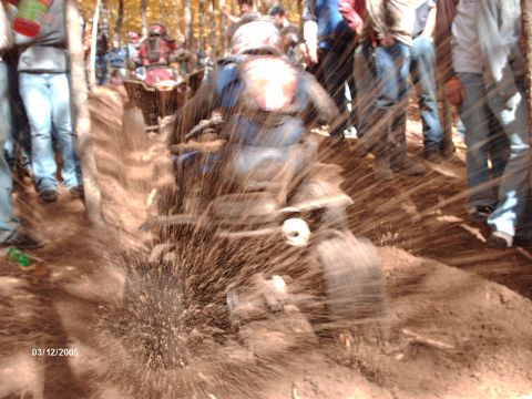 1995 Ford Probe - An ATV navigates a muddy track, kicking up water and dirt as onlookers observe the event.