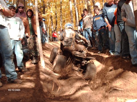 1995 Ford Probe - An ATV rider powers through a muddy rut while onlookers observe the action on a wooded trail.