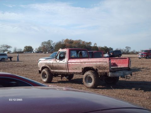 1995 Ford Probe - Muddy pickup truck in a field on a sunny day, with other vehicles present.