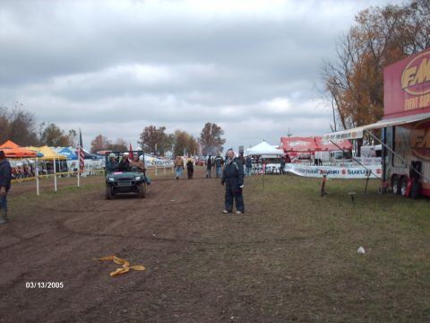 1995 Ford Probe - An outdoor event is underway with tents and trailers set up on a muddy field under an overcast sky.