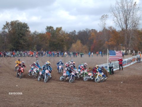 1995 Ford Probe - A group of motocross riders line up at the start of a race on a dirt track.