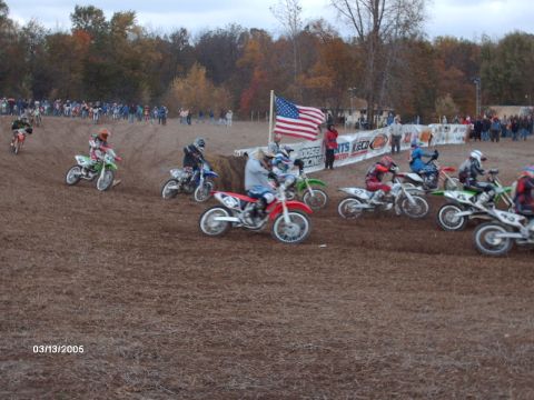 1995 Ford Probe - A group of motocross riders compete on a dirt track, with an American flag flying overhead.