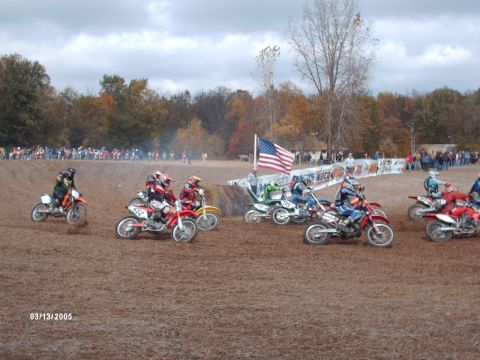 1995 Ford Probe - A group of dirt bike racers compete on a muddy track under an overcast sky.