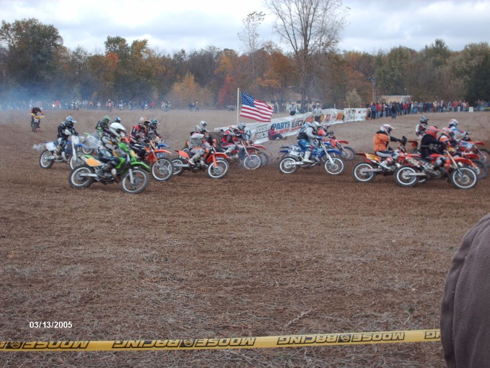 Motocross race start with multiple dirt bikes and riders on a dirt track