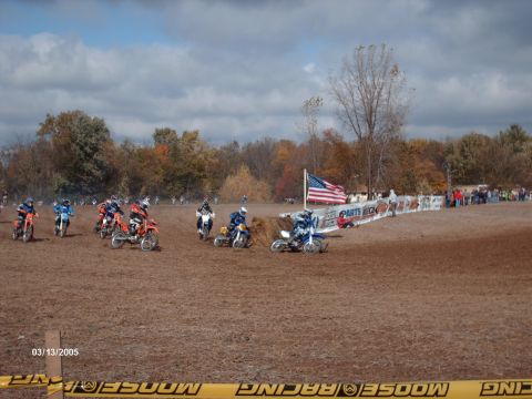 1995 Ford Probe - A group of dirt bike riders compete on a muddy track under a cloudy sky.