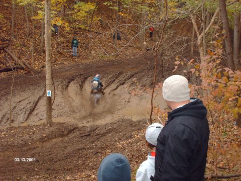 1995 Ford Probe - A motocross rider navigates a muddy track while onlookers observe the event.