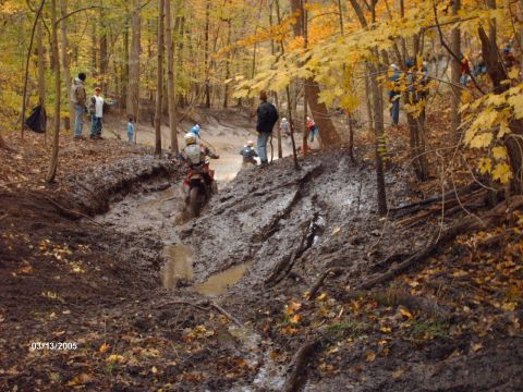 1995 Ford Probe - A motorcycle struggles through a deep mud pit during an off-road race event in the fall.