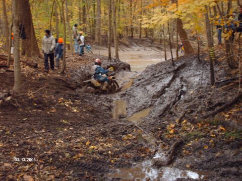 1995 Ford Probe - A motorcycle rider tackles a difficult muddy obstacle on a wooded trail.