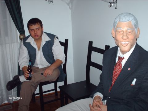 1995 Ford Probe - A man in a costume sits with a beer while another person wears a Bill Clinton mask at a gathering.
