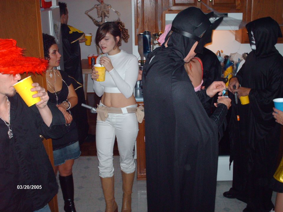 People in Halloween costumes holding drinks at a party. Date stamp reads 03/20/2005