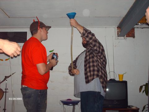 1995 Ford Probe - Two men participate in a drinking game using a funnel and tube in a basement setting.