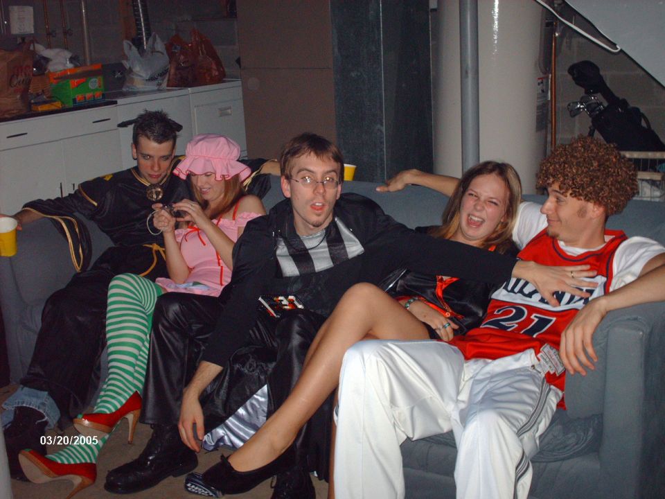 People in costumes on a couch, one holding a camera