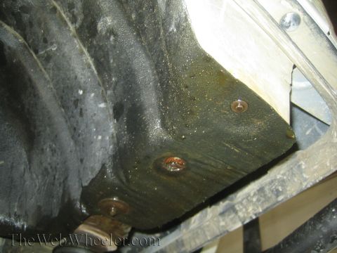1990 Ford Bronco - Close-up of a grimy black fender liner and inner wheel well with exposed mounting bolts inside a tire well.