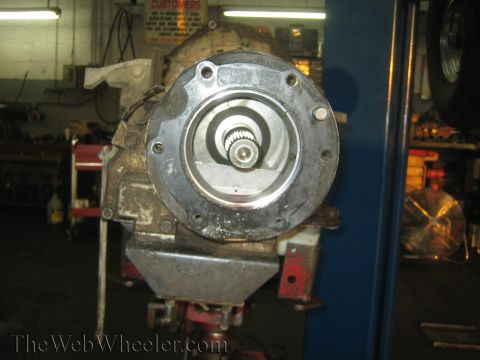 1990 Ford Bronco - removed gearbox sits in a shop, showing its circular bolt flange and a splined output shaft at center.