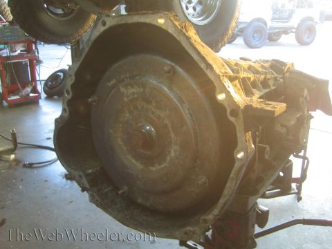 1990 Ford Bronco - front bellhousing of a transmission with its torque converter exposed, mounted on a stand in a repair shop.