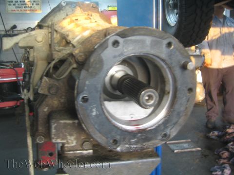 1990 Ford Bronco - Closeup of a transmission tailhousing with a splined output shaft protruding from its bolted circular flange.