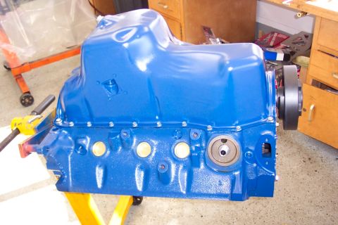 1978 Ford F-250 - A blue painted engine oil pan is mounted on an engine stand, with a black pulley visible on the right side.