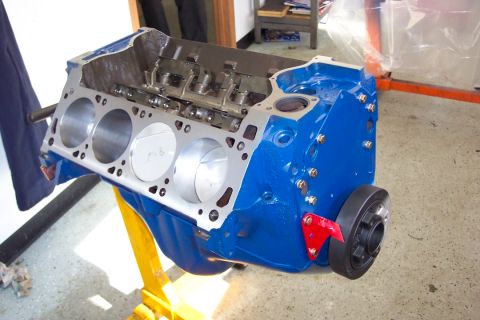 1978 Ford F-250 - A blue V8 engine block, likely undergoing rebuild or assembly, is shown on a yellow engine stand.
