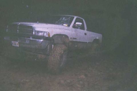 1978 Ford Bronco - A white pickup truck with large tires is seen off-road in muddy conditions.