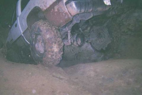 1978 Ford Bronco - This vehicle appears to be stuck in a muddy off-road situation, with its front tire and undercarriage visible.
