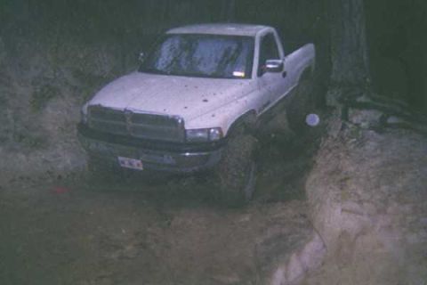 1978 Ford Bronco - A white pickup truck navigates a muddy off-road trail.