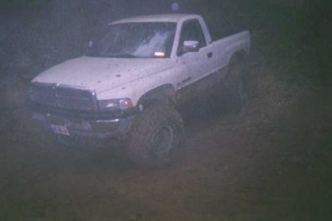 1978 Ford Bronco - A white pickup truck navigates a muddy, off-road course.