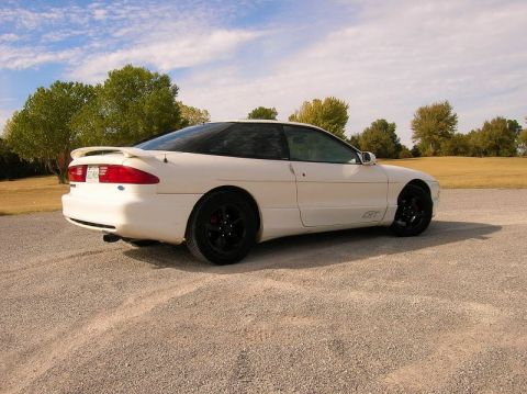 1993 Ford Probe - A white 1993 Ford Probe GT coupe is parked on a gravel road with trees and a field in the background.
