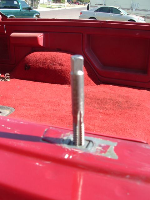 1990 Ford Bronco - A tap tool is shown in the bed of a red truck, with another green truck visible in the background.