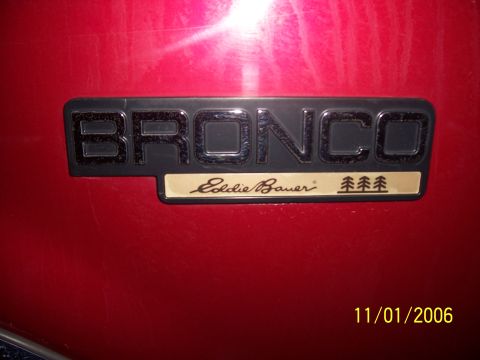 1994 Ford Bronco - Close-up of a Bronco Eddie Bauer emblem on a red vehicle's exterior.