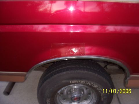1994 Ford Bronco - Close-up of a red vehicle's rear fender showing damage and a tire.