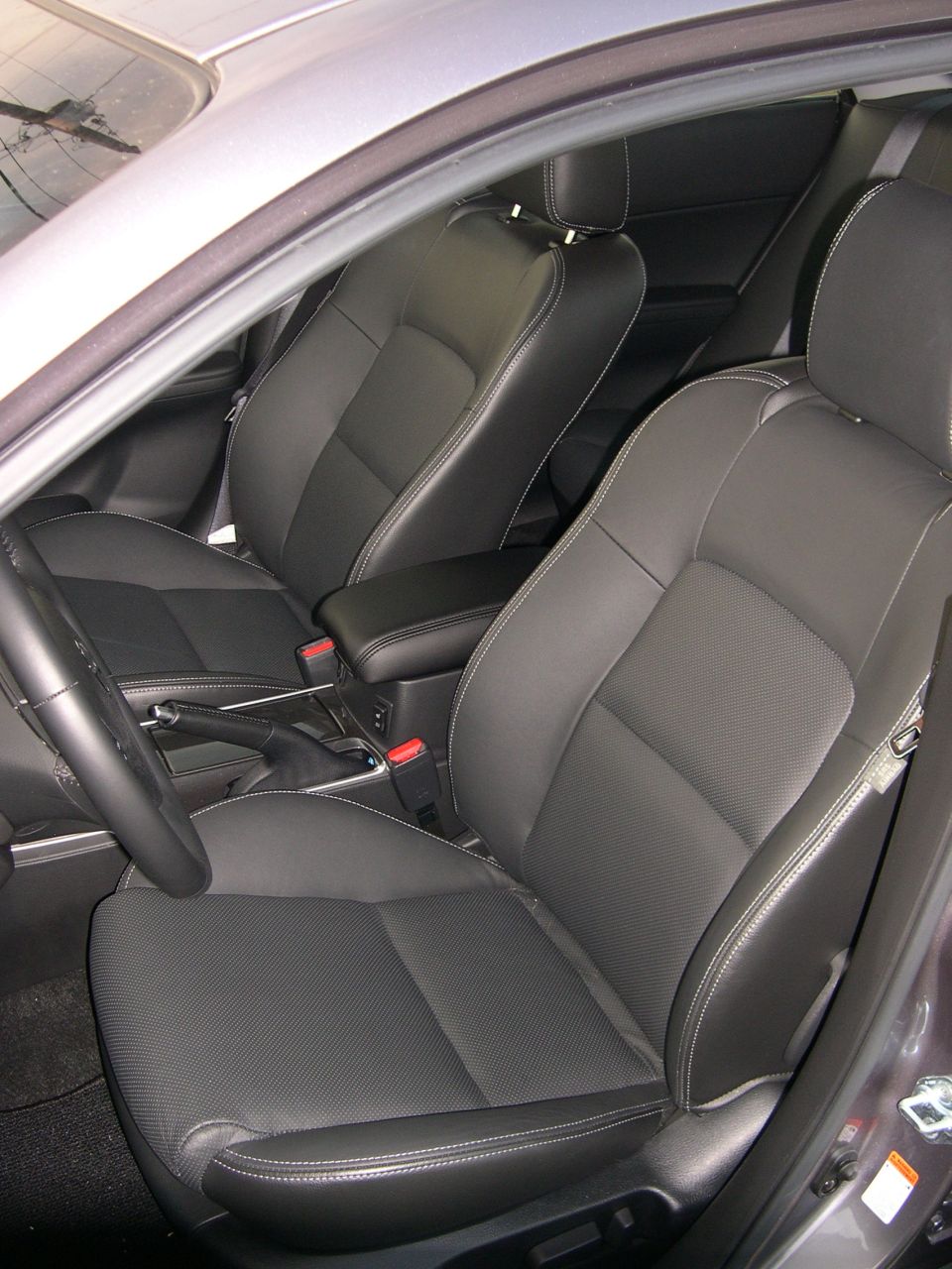 Car interior showing front seats, armrest, and dashboard details